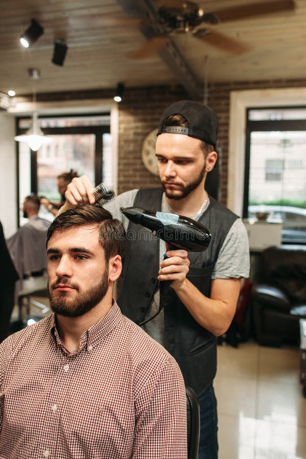Стилизатор делая современный hairdo для молодого человека стоковые фотографии rf Стилизатор делая современный hairdo для молодого человека стоковые фотографии rf