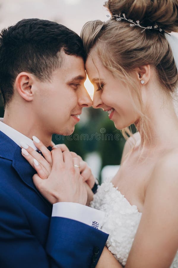 Стильный счастливый жених и невеста представляя в теплом свете захода солнца на приеме по случаю бракосочетания outdoors Шикарные стоковые изображения rf Стильный счастливый жених и невеста представляя в теплом свете захода солнца на приеме по случаю бракосочетания outdoors Шикарные стоковые изображения rf