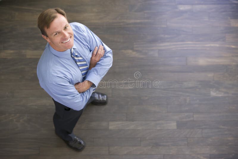 Businessman standing indoors smiling looking up at camera. Businessman standing indoors smiling looking up at camera.