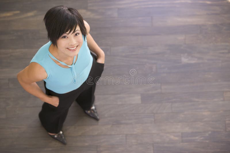 Businesswoman standing indoors smiling looking upwards. Businesswoman standing indoors smiling looking upwards