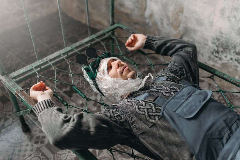 Странный человек оборачивает его голову в фильме и лежит в кровати стоковая фотография Странный человек оборачивает его голову в фильме и лежит в кровати стоковая фотография