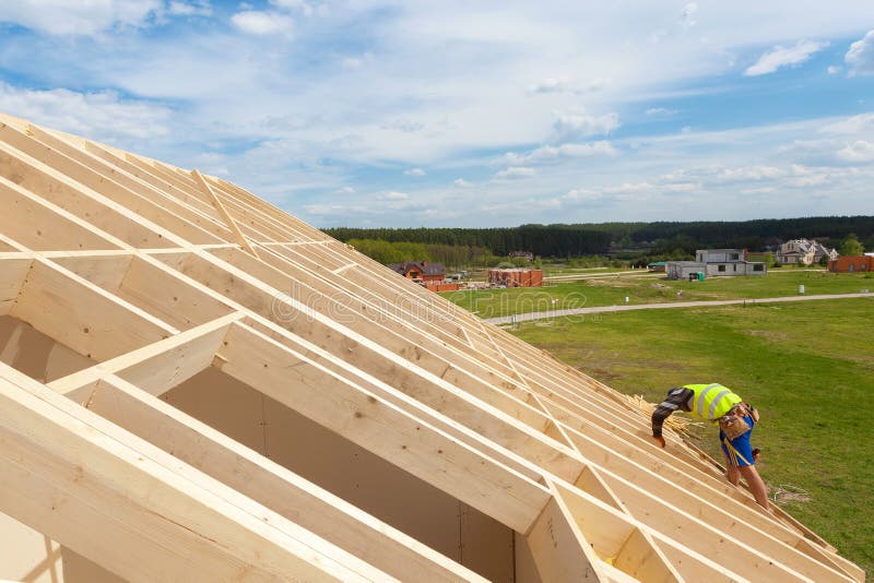 Строительная бригада работая на крыше против голубого неба Редакционное ...