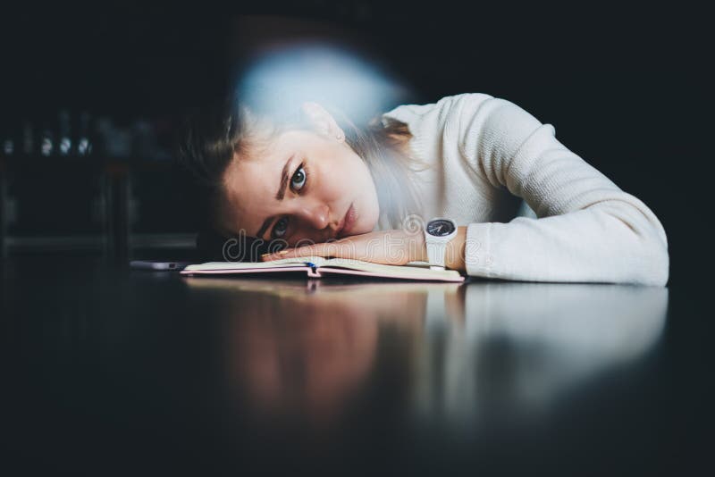 Студент лежит на столе и уставший, делая домашнее задание стоковые изображения