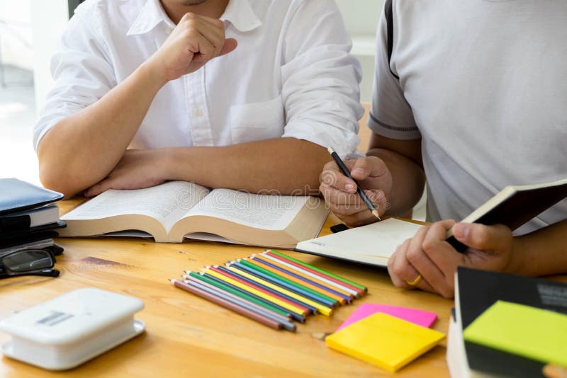 Студенты помогают преподавательству друга и вопрос учить дополнительный в библиотеке o стоковая фотография Студенты помогают преподавательству друга и вопрос учить дополнительный в библиотеке o стоковая фотография