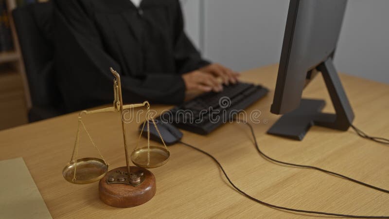 судья набирает текст на клавиатуре в офисе с весами правосудия на переднем плане стоковая фотография