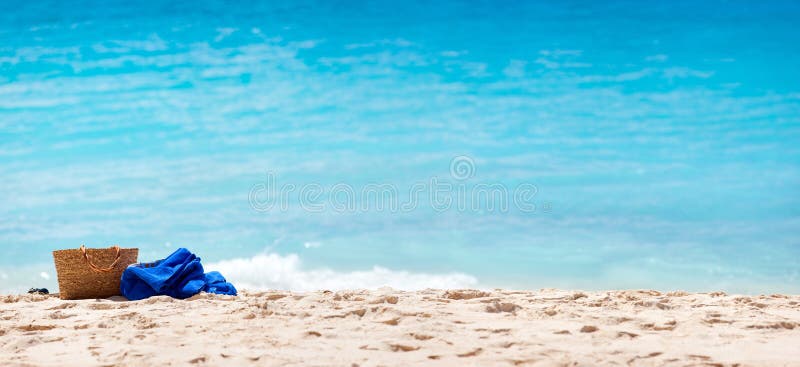 Panorama of a tropical beach with straw bag and towel on a sand. Panorama of a tropical beach with straw bag and towel on a sand