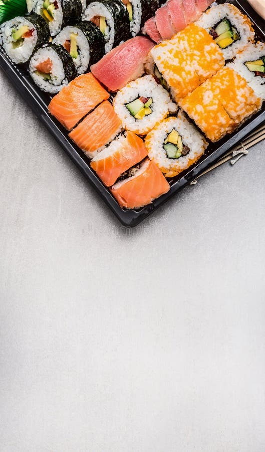 Суши установленные с кренами nigiri тунца, внутренних и внешних в коробке перехода на серой каменной предпосылке, взгляд сверху стоковое изображение Суши установленные с кренами nigiri тунца, внутренних и внешних в коробке перехода на серой каменной предпосылке, взгляд сверху стоковое изображение