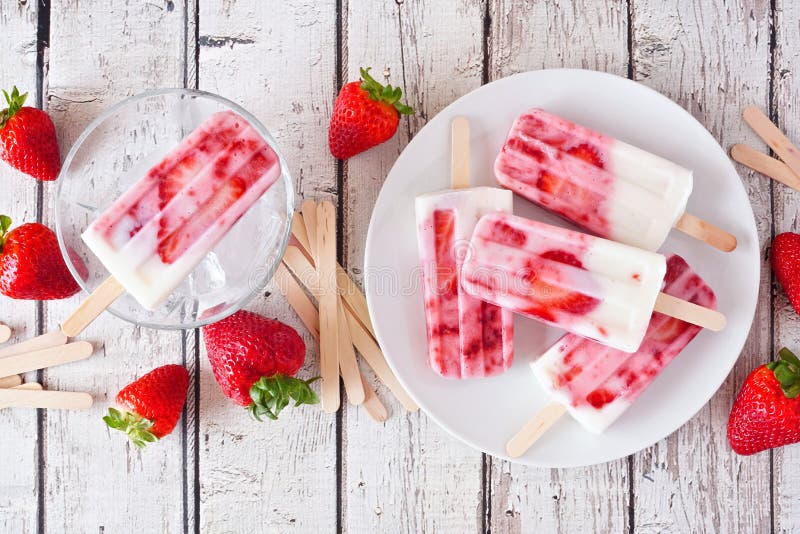 Сцена вид сверху popsicles йогурта домашней клубники ванильная на деревенскую белой дерева стоковые изображения
