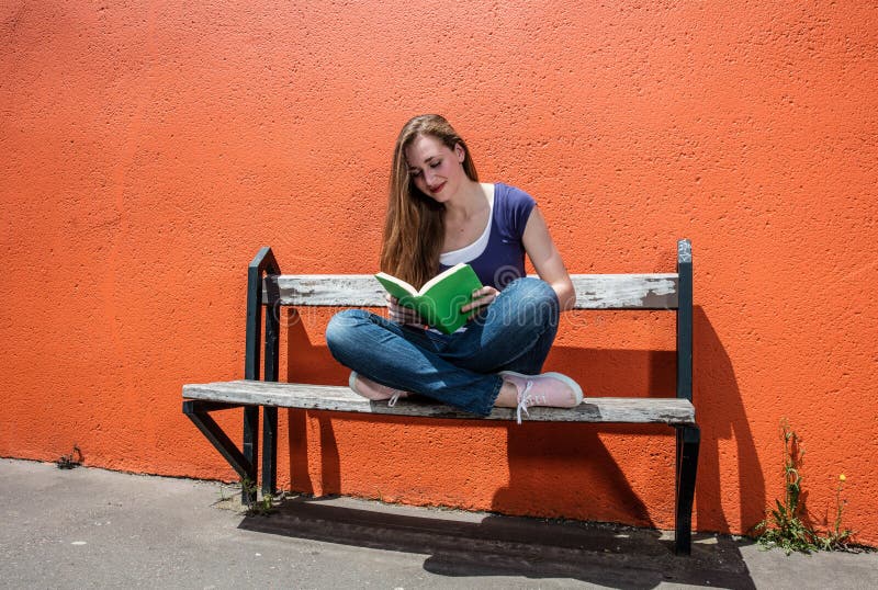 Счастливая книга чтения молодой женщины для мирного пролома в улице стоковая фотография Счастливая книга чтения молодой женщины для мирного пролома в улице стоковая фотография