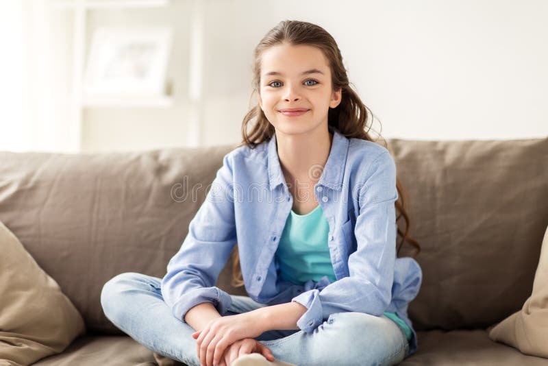 Счастливая усмехаясь девушка preteen сидя на софе дома стоковые изображения