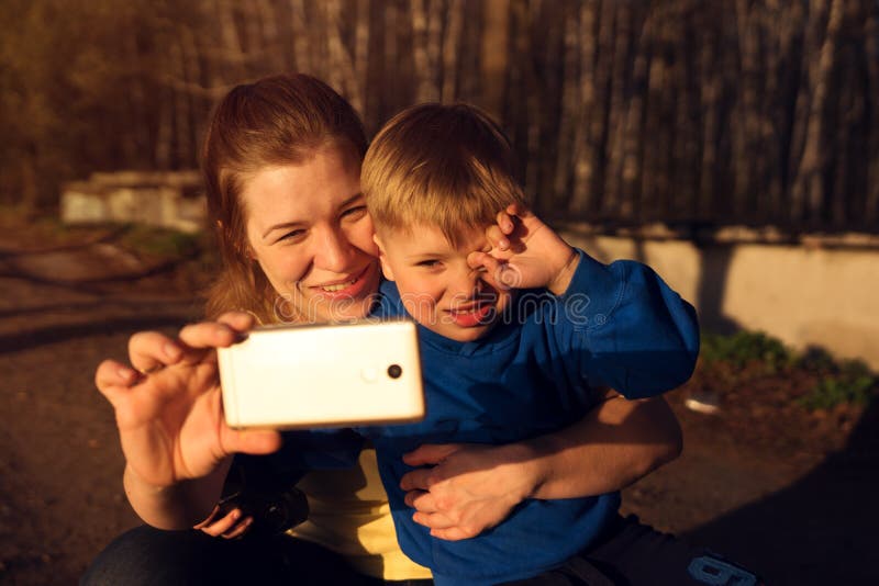 Счастливая усмехаясь семья делая selfie на заходе солнца стоковое изображение rf Счастливая усмехаясь семья делая selfie на заходе солнца стоковое изображение rf
