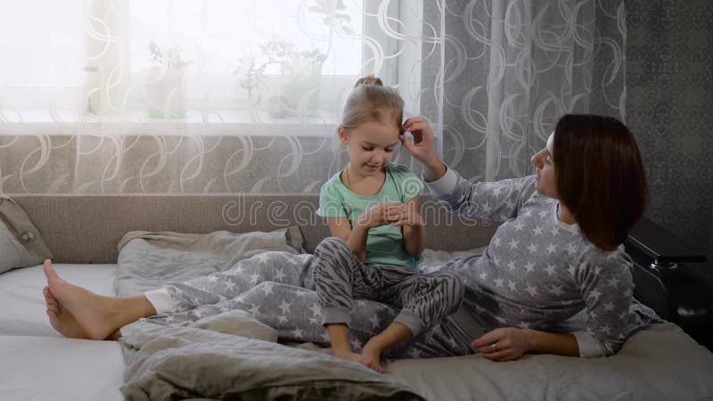 Счастливая любящая семья тратит время совместно во времени ложиться спать играя и обнимая Усмехаясь дочь и мать одетые внутри сток-видео