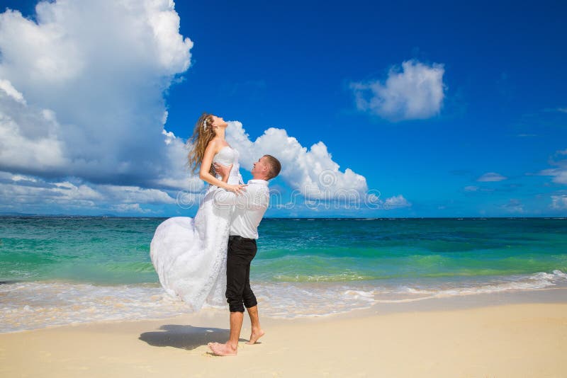 Счастливый жених и невеста имея потеху на тропическом пляже Wedding стоковое изображение