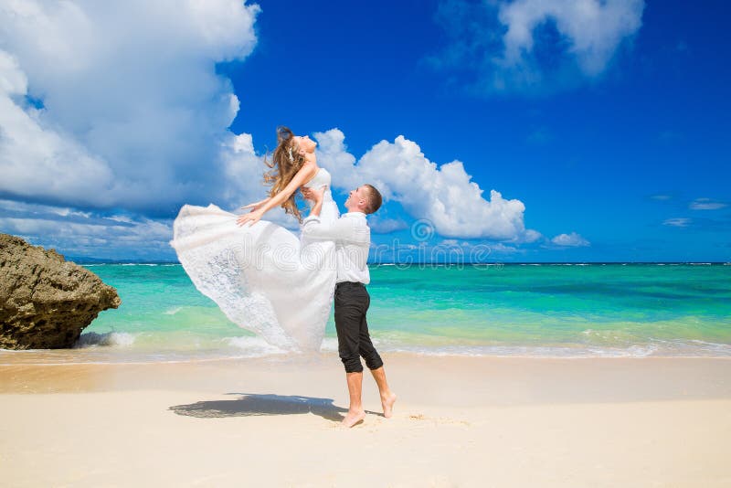 Счастливый жених и невеста имея потеху на тропическом пляже Wedding стоковые фотографии rf