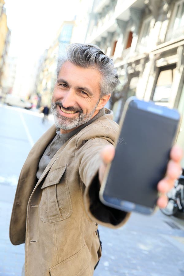 Счастливый зрелый человек показывая smartphone стоковое фото