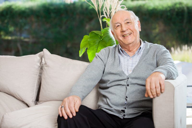 Portrait of happy senior man sitting on couch at nursing home porch. Portrait of happy senior man sitting on couch at nursing home porch