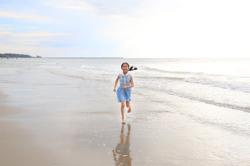 счастливая азиатская девочка, веселая, бегающая на тропическом песке на рассвете стоковые фото