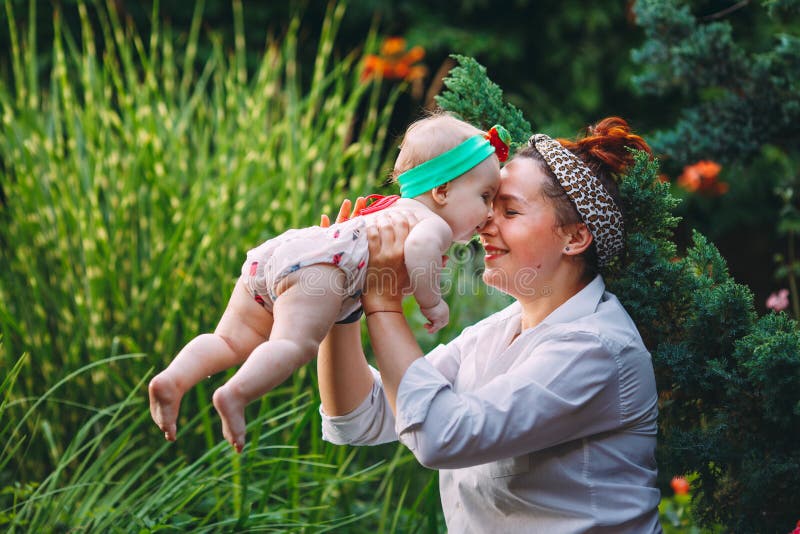 Счастливая гармоничная семья outdoors мать бросает младенца вверх, смеющся и играющ летом на природе стоковое изображение Счастливая гармоничная семья outdoors мать бросает младенца вверх, смеющся и играющ летом на природе стоковое изображение