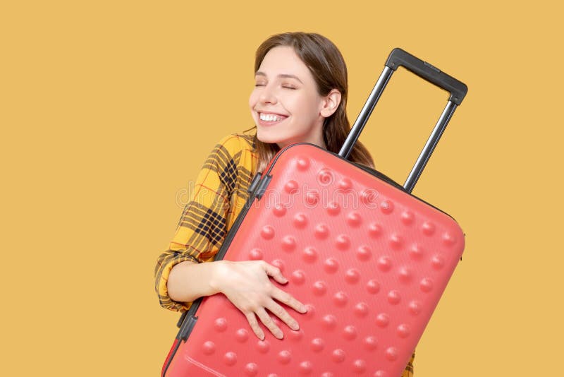 Dream, travel. Happy smiling young long-haired girl with closed eyes hugging a red suitcase. Dream, travel. Happy smiling young long-haired girl with closed eyes hugging a red suitcase.