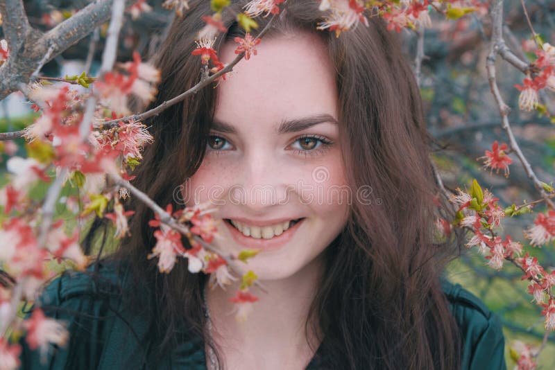 Счастливая девушка спрятать ее усмехаясь сторону в ветвях зацветая ви стоковые фото Счастливая девушка спрятать ее усмехаясь сторону в ветвях зацветая ви стоковые фото