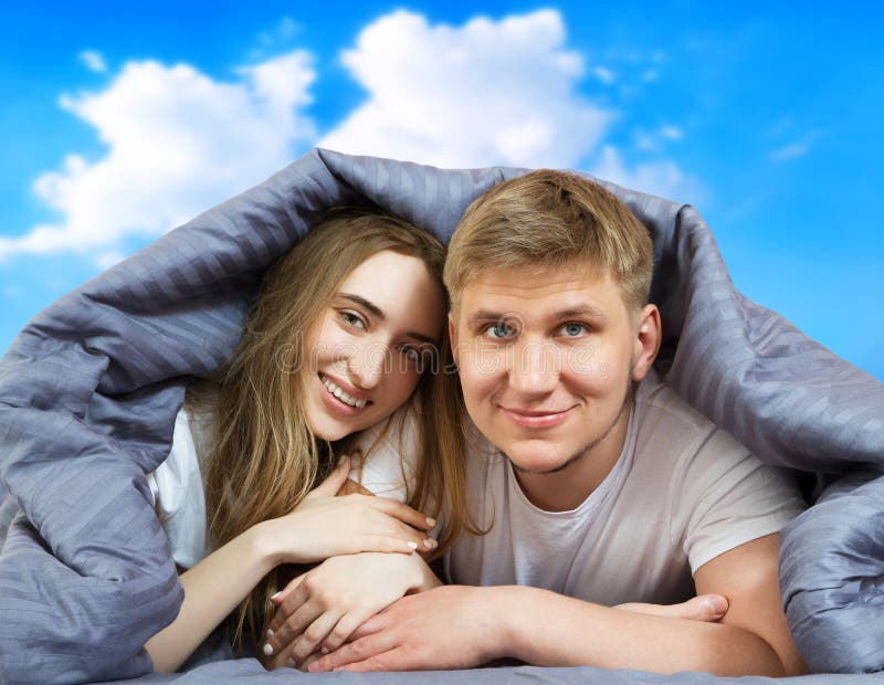 счастливая красивая пара в постели, изолированная на фоне голубого неба, оставаясь дома концепция, коронавирусный карантинный фон стоковое фото rf