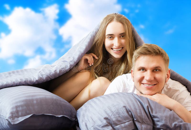 счастливая красивая пара в постели, изолированная на фоне голубого неба, оставаясь дома концепция, коронавирусный карантинный фон стоковое фото rf