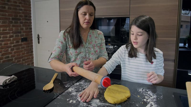 Счастливая мать и дочь, сваривая тесто на кухне, печь печенье видеоматериал