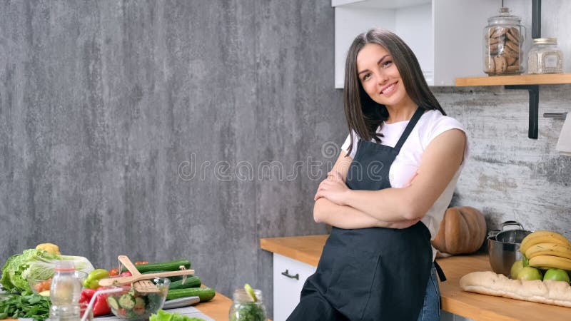 Счастливая молодая женщина в фартуке позирует на кухне у себя дома с положительными эмоциями видеоматериал