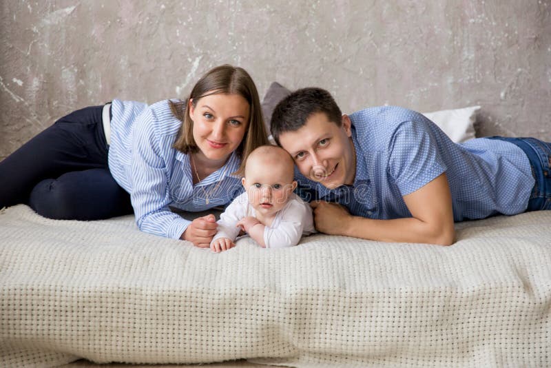 Счастливая молодая кавказская семья лежа на кровати стоковые изображения Счастливая молодая кавказская семья лежа на кровати стоковые изображения