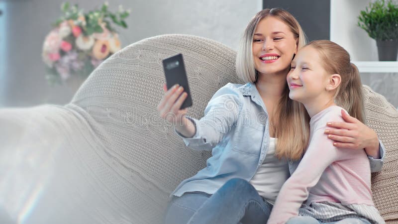 Счастливая молодая мать и дочь-подростки позируют селфи, используя смартфон расслабляющего дома сток-видео