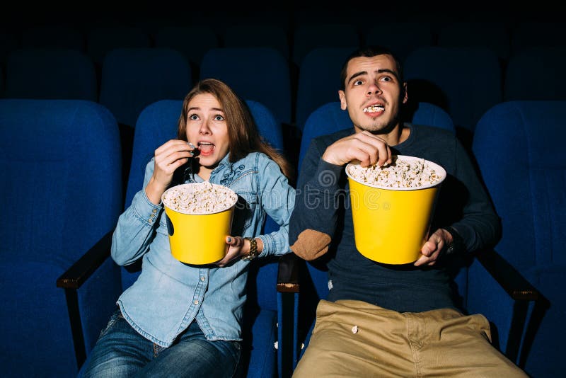 Счастливая молодая пара смотрит комедийный фильм в кино, улыбаясь стоковое изображение rf