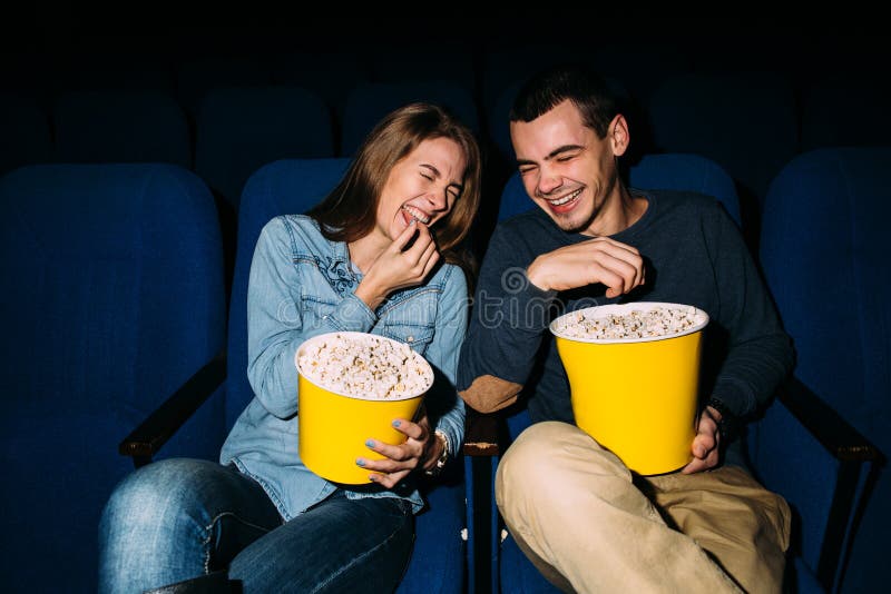 Счастливая молодая пара смотрит комедийный фильм в кино, улыбаясь стоковое изображение rf