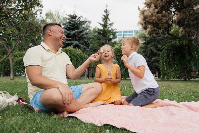 Счастливая семья весело проводит пикник в парке стоковые фотографии rf