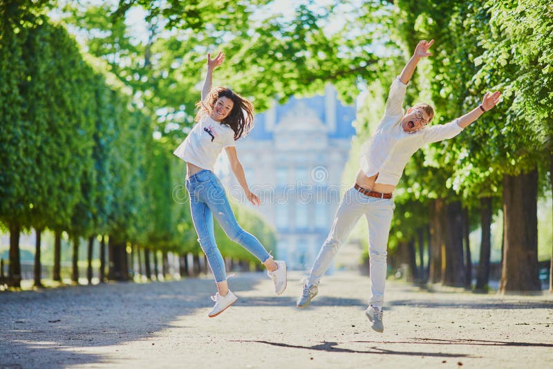Счастливой романтической парой в Париже, прыгающей в саду Tuileries стоковые фотографии rf Счастливой романтической парой в Париже, прыгающей в саду Tuileries стоковые фотографии rf