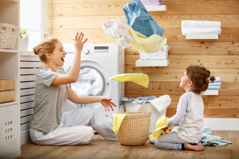 Счастливые домохозяйка и ребенок матери семьи в прачечной с washin стоковое фото