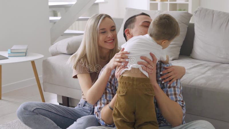 счастливые молодые взрослые родители играли на полу в современной гостиной. видеоматериал