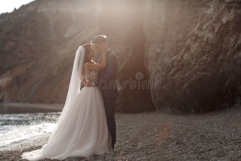 Счастливые пары влюбленн в groom и невеста на фоне гор около голубого океана стоковое фото rf Счастливые пары влюбленн в groom и невеста на фоне гор около голубого океана стоковое фото rf