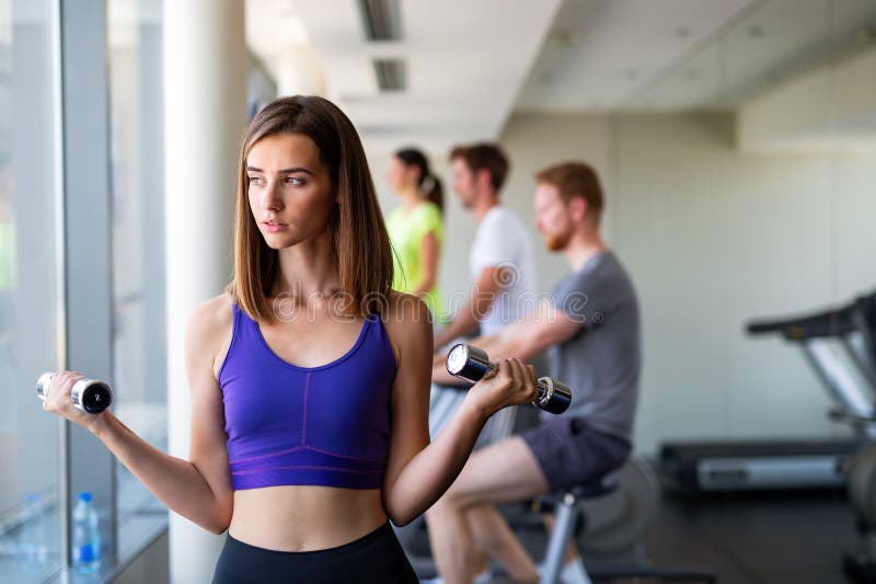 счастливые улыбки фитнес-девушка подъема Dumbbell утром в современном спортзале, чтобы оставаться здоровым. стоковое фото