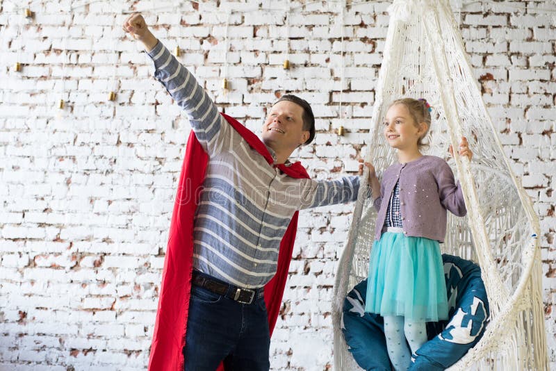 Счастливый отец в костюме superhero и его дочь в гамак. Концепция дня отцов.