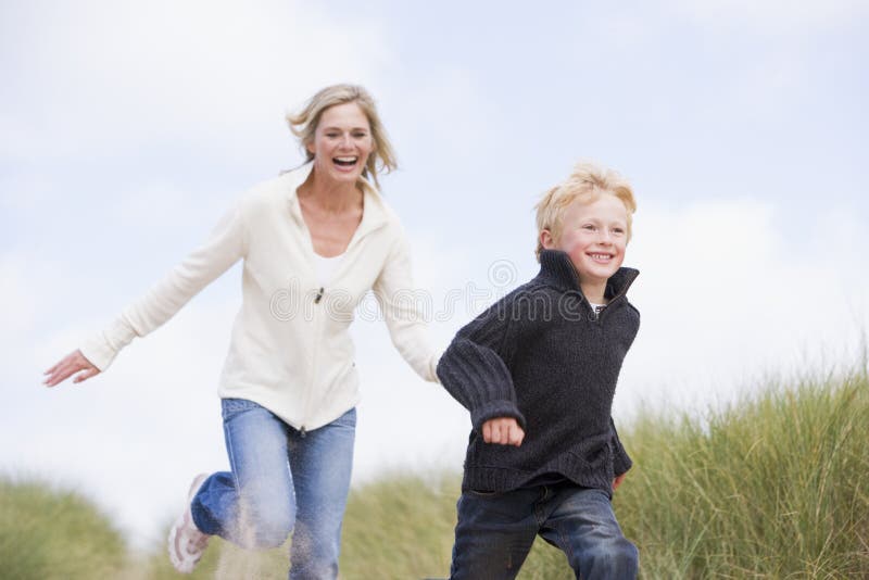 Mother and son running on beach smiling. Mother and son running on beach smiling.