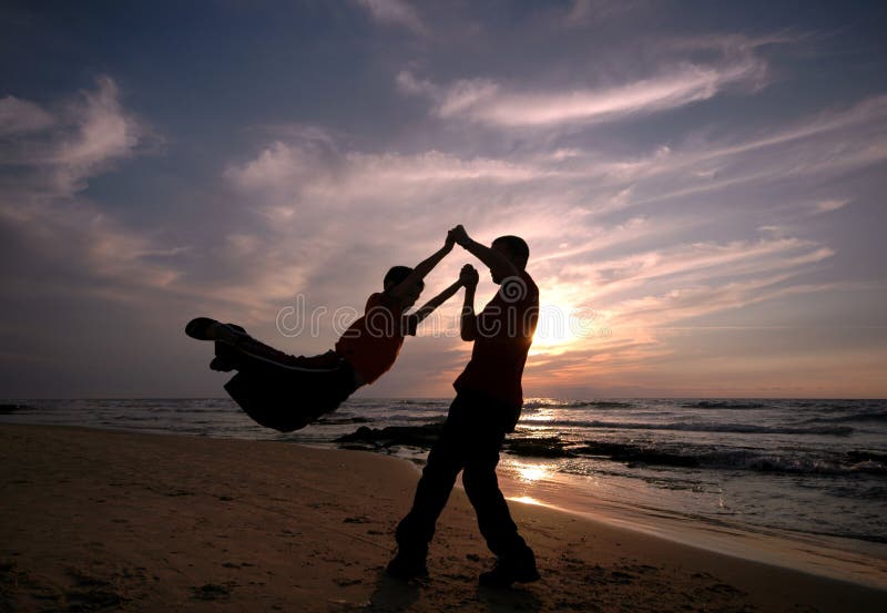 Father and son playing on the beach at sunset. Father and son playing on the beach at sunset