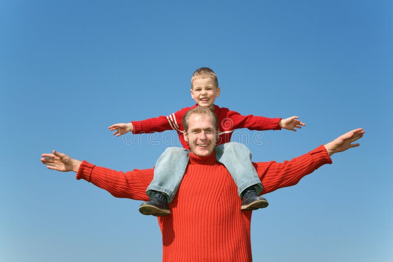 Father with son on shoulders on a background of the blue sky. Father with son on shoulders on a background of the blue sky