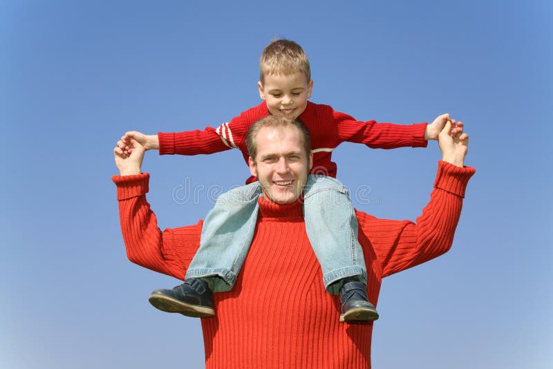 Father with son on shoulders on a background of the blue sky. Father with son on shoulders on a background of the blue sky