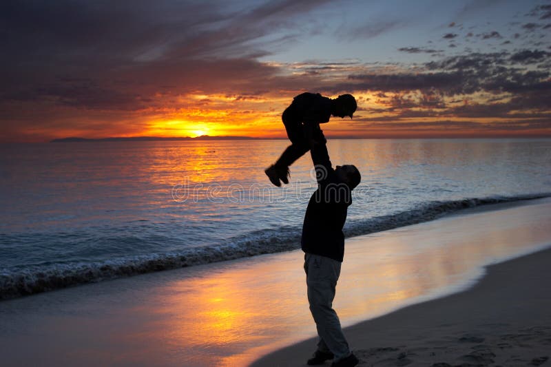 Father and son playing together on a beach at sunset. Father and son playing together on a beach at sunset