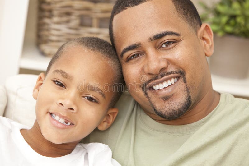 A happy African American man and boy, father and son, family sitting together at home. A happy African American man and boy, father and son, family sitting together at home