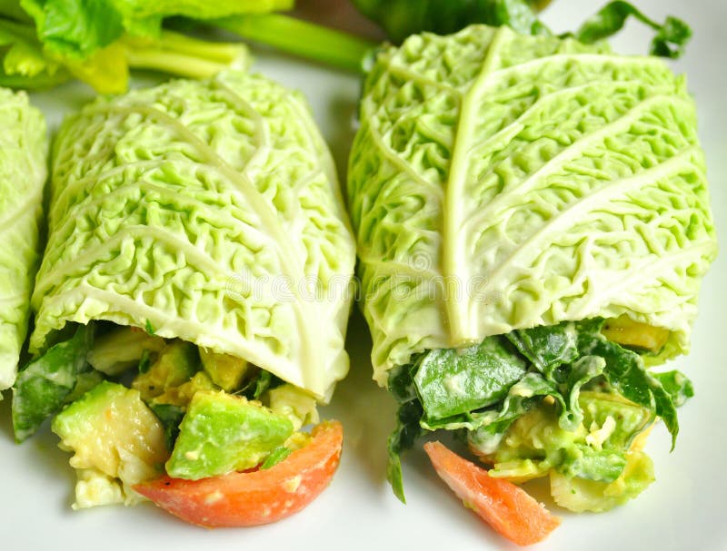 Raw food diet concept with cabbage wraps filled with tomato , spinach and avocado . vegan dish with fresh vegetables. detox, detoxification diet. Raw food diet concept with cabbage wraps filled with tomato , spinach and avocado . vegan dish with fresh vegetables. detox, detoxification diet.