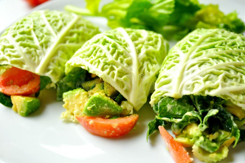 Raw food diet concept with cabbage wraps filled with tomato , spinach and avocado . vegan dish with fresh vegetables. detox, detoxification diet. Raw food diet concept with cabbage wraps filled with tomato , spinach and avocado . vegan dish with fresh vegetables. detox, detoxification diet.