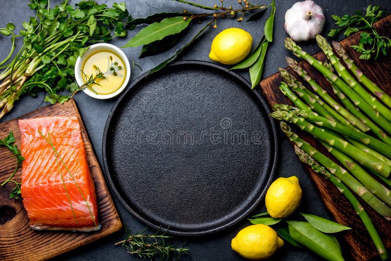 Сырцовые salmon филе, спаржа, лимоны и травы вокруг плиты литого железа Еда варя предпосылку с космосом экземпляра Взгляд сверху стоковые фото Сырцовые salmon филе, спаржа, лимоны и травы вокруг плиты литого железа Еда варя предпосылку с космосом экземпляра Взгляд сверху стоковые фото