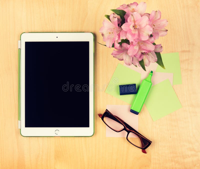 Office table with digital tablet, reading glasses and sticky notes. View from above with copy space. Office table with digital tablet, reading glasses and sticky notes. View from above with copy space