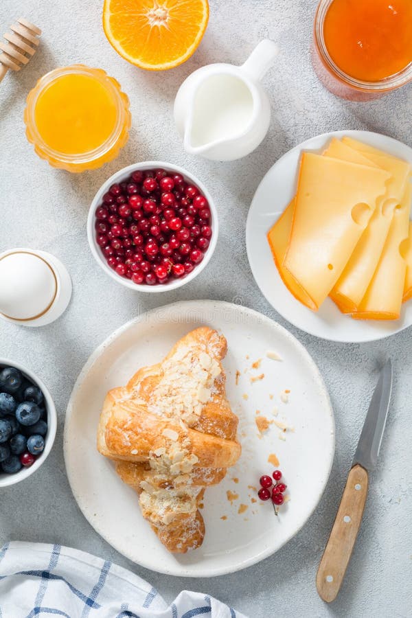 Таблица завтрака, еда континентального завтрака Круассан, сыр, варенье, ягоды, мед и яичко